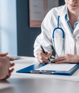Doctor sitting at desk and writing a prescription for her patient