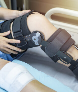 Asian woman patient with bandage compression knee brace support injury on the bed in nursing hospital.healthcare and medical support.