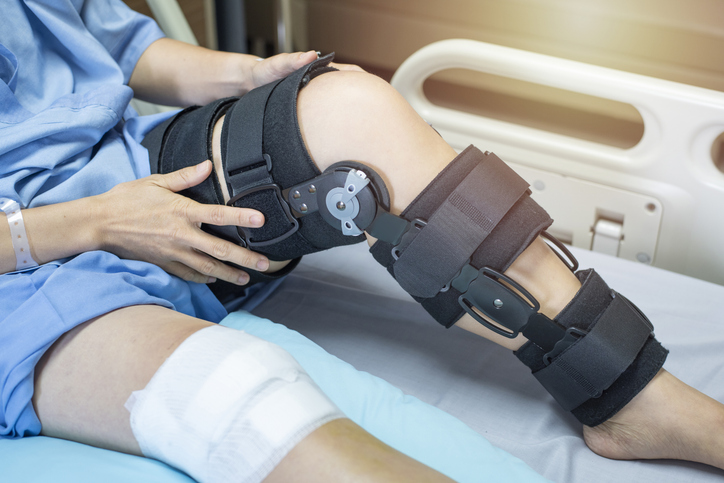 Asian woman patient with bandage compression knee brace support injury on the bed in nursing hospital.healthcare and medical support.